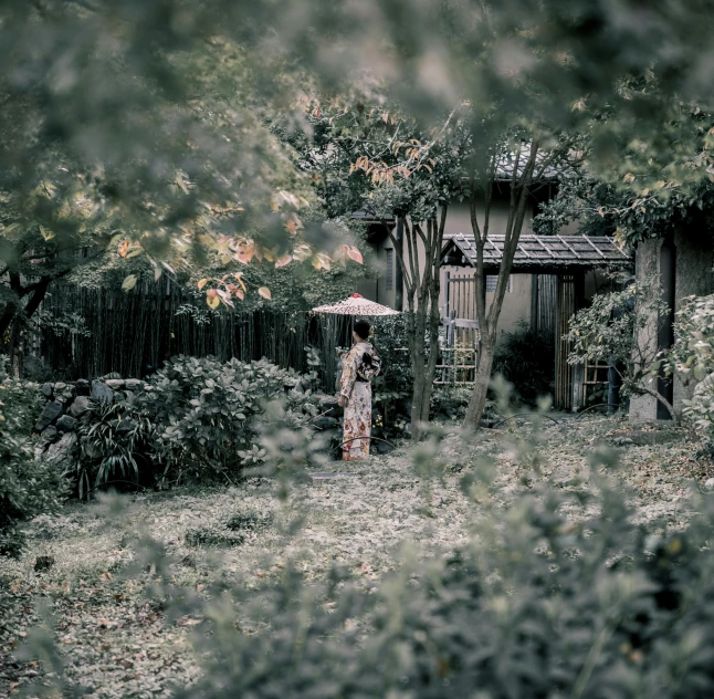 a woman holding an umbrella in a garden, inspired by Maruyama Ōkyo, unsplash, solitary cottage in the woods, desaturated, amongst foliage, ground - level medium shot