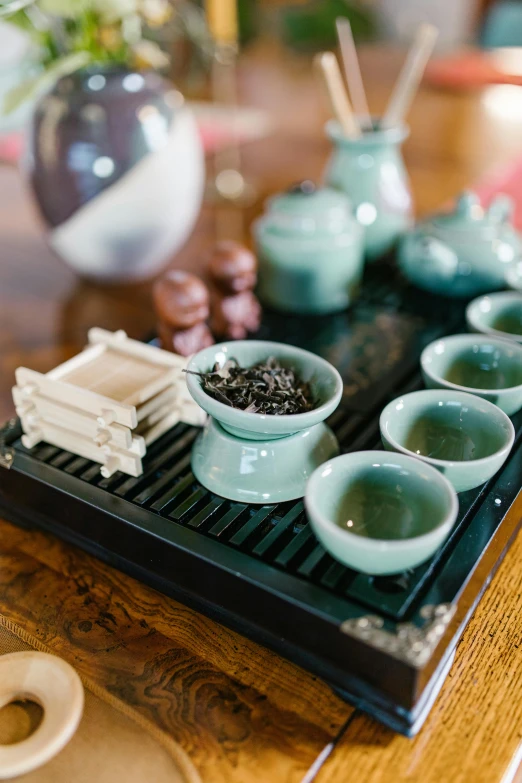 a tray filled with cups and saucers on top of a wooden table, inspired by Xuande Emperor, spa, mint, small chin