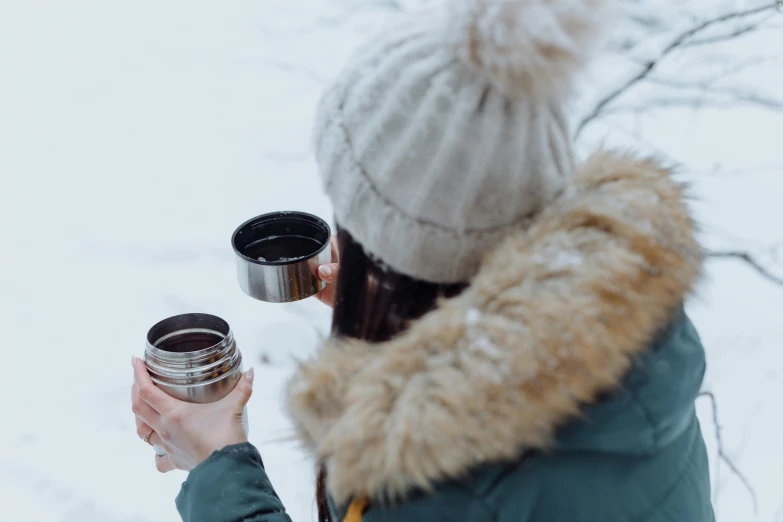 a woman holding a cup of coffee in the snow, trending on pexels, holding a tin can, avatar image, picnic, stainless steal