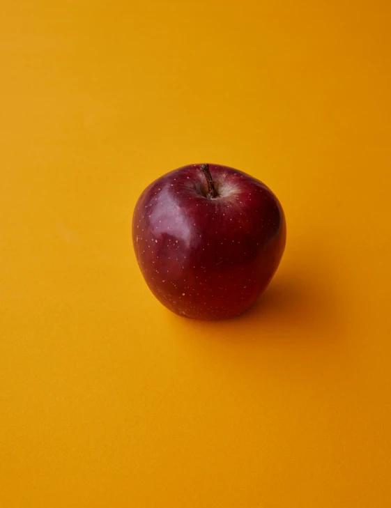 a red apple sitting on top of a yellow surface, profile image