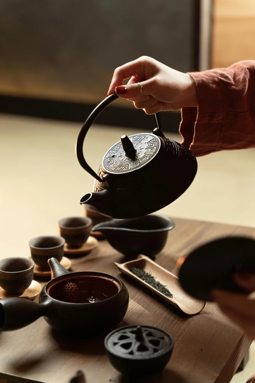 a person pouring tea into a tea pot, inspired by Sesshū Tōyō, trending on unsplash, square, traditional korean interior, black, made of glazed