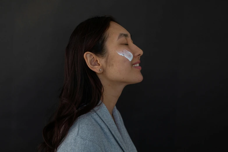 a woman with a lot of cream on her face, trending on pexels, seen from the side, detailed product image, asian female, chalk white skin