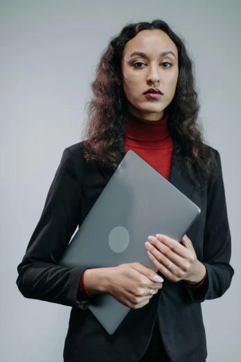 a woman holding a laptop computer in her hands, an album cover, trending on pexels, grey metal body, formal portrait, thinkpad, faridah malik
