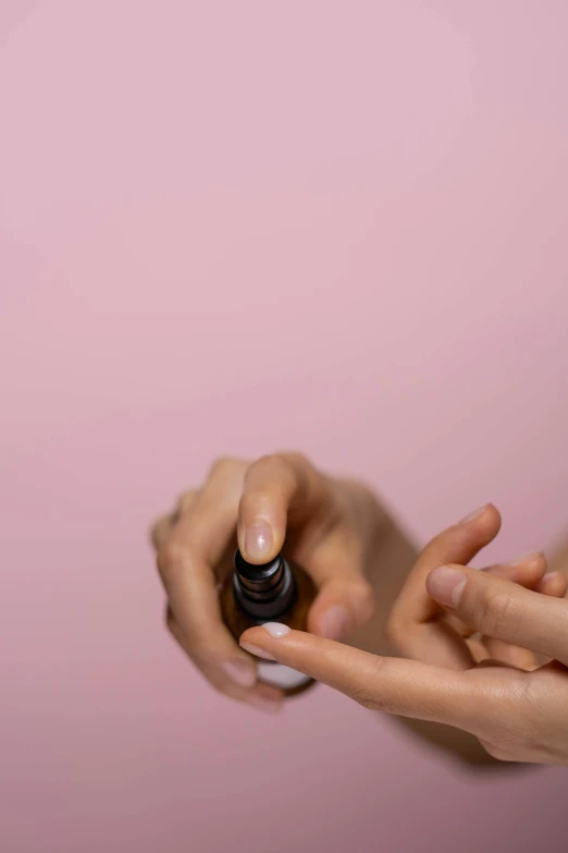 a close up of a person holding a bottle of liquid, by Olivia Peguero, cosmetics, pink, spiralling, finger