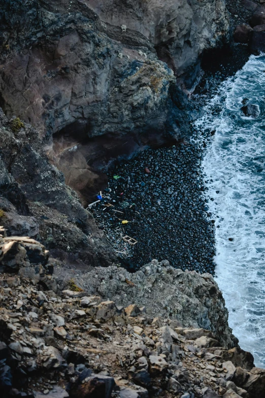 a man riding a surfboard on top of a rocky beach, inspired by Andreas Gursky, pexels contest winner, piles of bodies, azores, high view, deep chasm