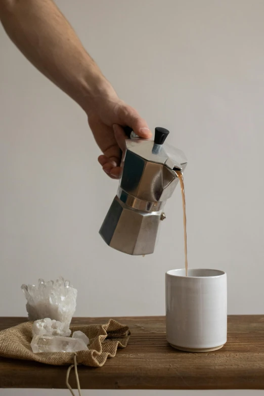 a person pouring coffee into a cup on a table, inspired by Hendrik Gerritsz Pot, made of carrara marble, aluminum, thumbnail, tall