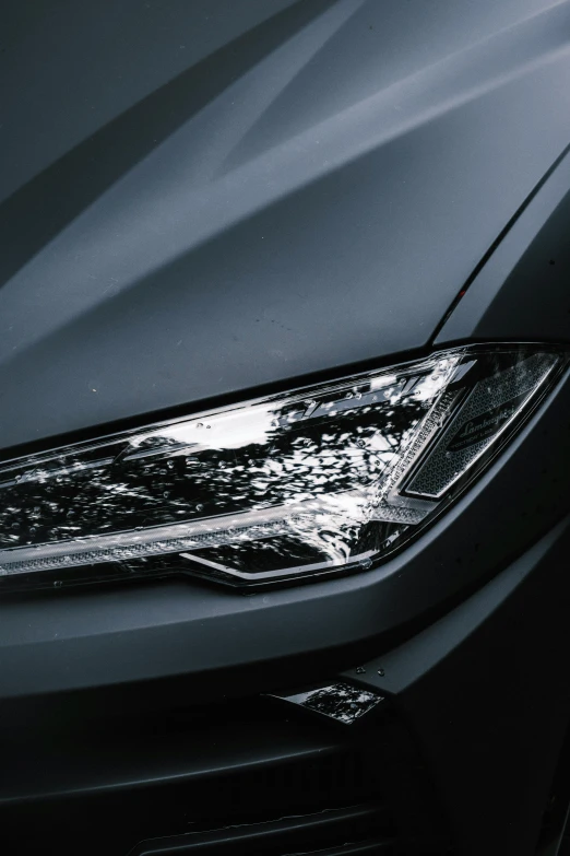 a close up of the headlights of a black car, pexels contest winner, side lighting xf iq4, shiny silver, reflective material, front