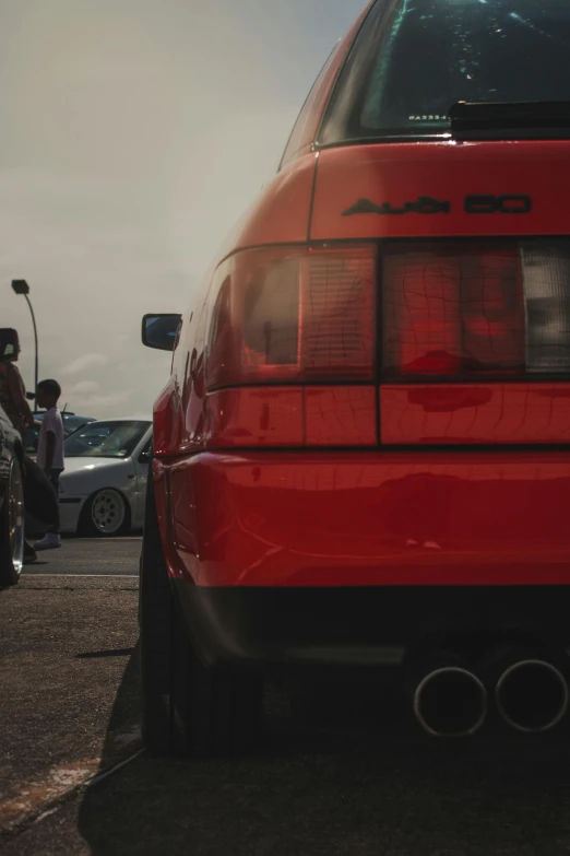 a red car is parked in a parking lot, by Adam Marczyński, unsplash, photorealism, ae 8 6, rear view, cars and people, 15081959 21121991 01012000 4k