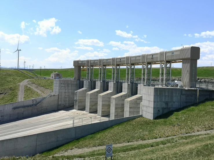 a large concrete structure sitting on top of a green field, wall of water either side, wyoming, electricity archs, slide show