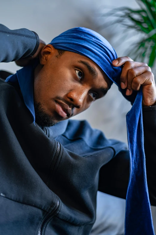 a man in a blue turban sitting on a couch, inspired by Paul Georges, trending on pexels, mrbeast, sweating, grim fashion model looking up, j. h. williams iii