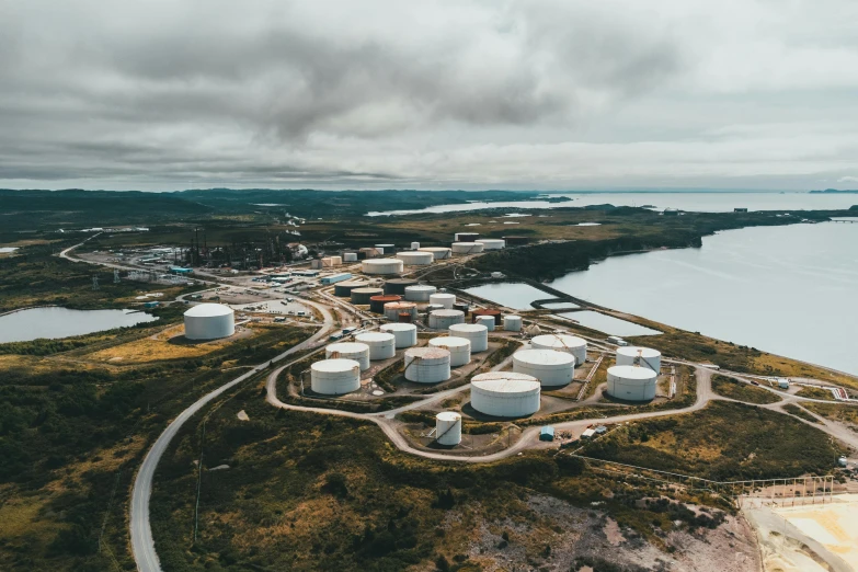 a large body of water next to a large body of water, a tilt shift photo, by Jesper Knudsen, pexels contest winner, propane tanks, industrial complex, all enclosed in a circle, skye meaker