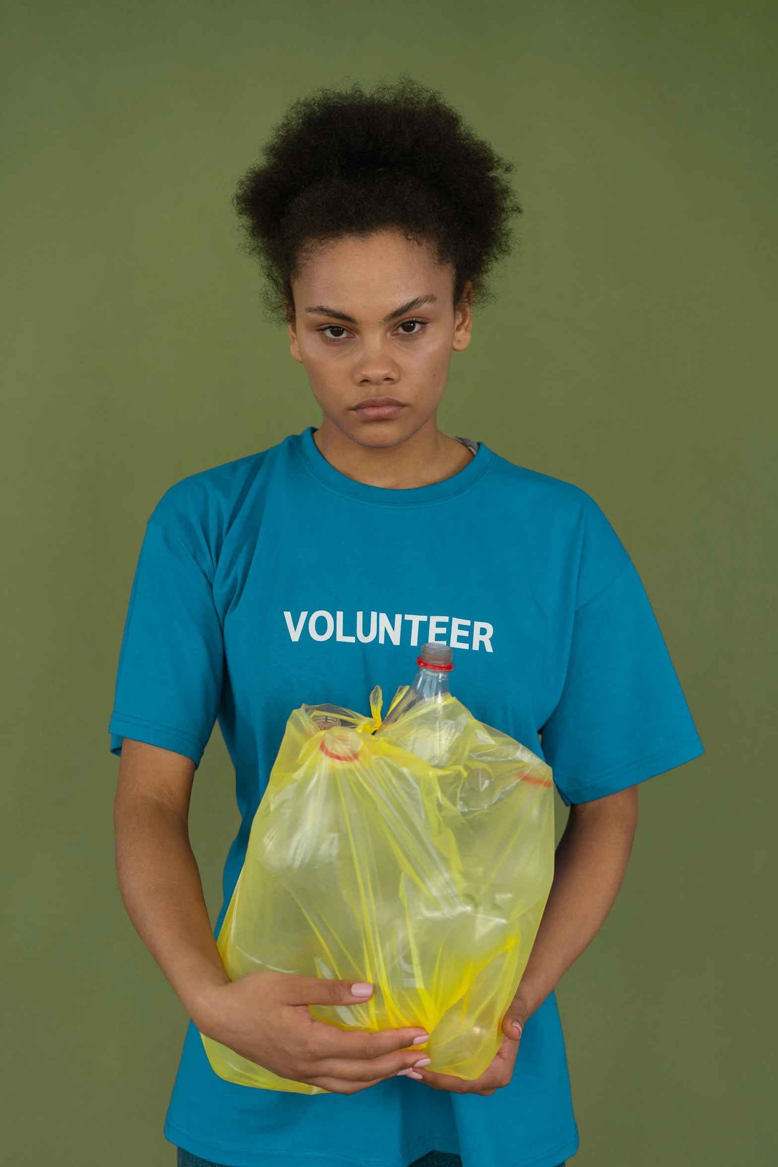 a woman in a blue shirt holding a yellow bag, inspired by Elsa Bleda, cg society contest winner, mad trash bags, press shot, worthless, teal