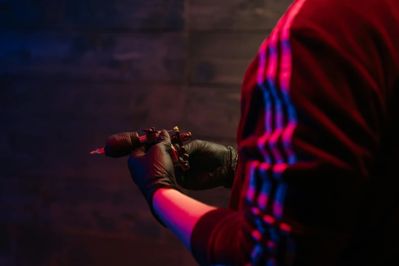 a close up of a person holding a glove, a tattoo, neon lighting and spotlights, it has a red and black paint, taken in the early 2020s, sublighting