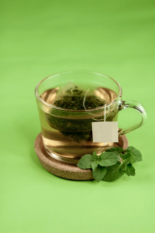 a cup of tea sitting on top of a coaster, a digital rendering, pexels, hurufiyya, mint leaves, thumbnail, green water, healthy