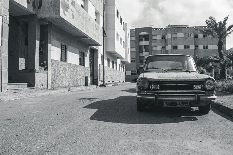 a black and white photo of a car parked in front of a building, by Nathalie Rattner, pexels contest winner, moroccan city, seventies, renault, sunfaded