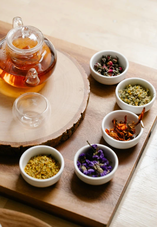 a tea pot sitting on top of a wooden cutting board, botanicals, thumbnail, seeds, honey
