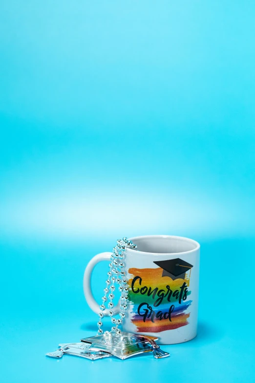 a coffee mug with a graduation cap on it, by Lynn Pauley, cyan photographic backdrop, pride, 1, day setting
