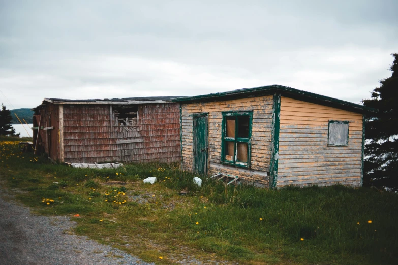 a small wooden building sitting on the side of a road, by Brigette Barrager, unsplash, photo of poor condition, inuit heritage, ignant, coloured photo