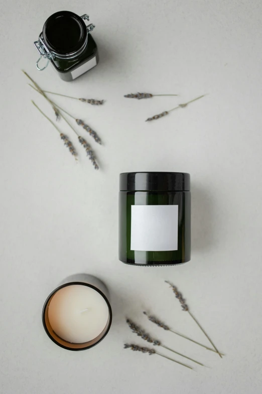 a candle sitting on top of a table next to some plants, trending on pexels, minimalism, lots of jars and boxes of herbs, clean face and body skin, thumbnail, bottle