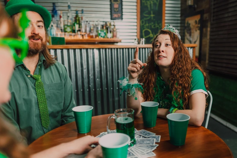 a group of people sitting around a wooden table, green, bitches brew, irish, profile image