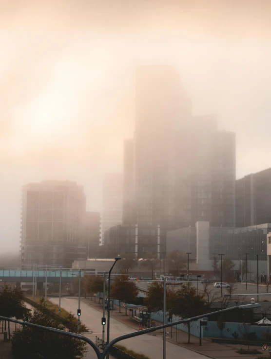 a view of a city on a foggy day, a matte painting, by Ryan Pancoast, pexels contest winner, tonalism, minneapolis, light pink mist, light orange mist, foggy day outside