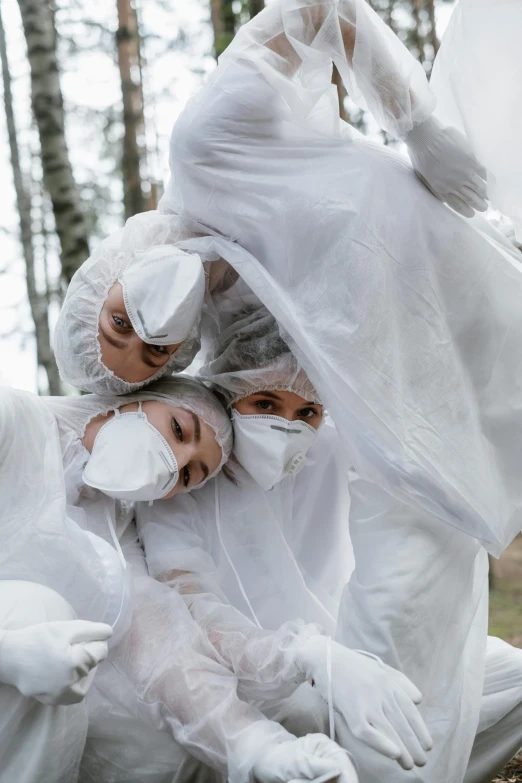 a group of people dressed in white in the woods, an album cover, by Adam Marczyński, pexels contest winner, environmental art, covered in bandages, hazmat suits, playful, upclose