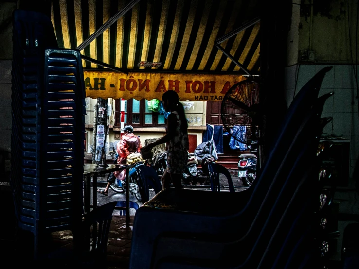 a couple of people standing in front of a store, by Julia Pishtar, unsplash contest winner, vietnam, dimly lit dive bar, people outside eating meals, shady alleys