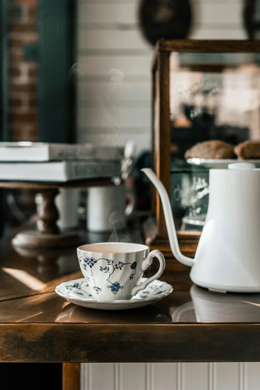 a white tea pot sitting on top of a wooden table, inspired by Richmond Barthé, pexels contest winner, rococo, cafe interior, blue, brown, grey