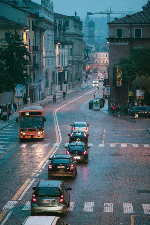 a street filled with lots of traffic next to tall buildings, inspired by Elsa Bleda, pexels contest winner, renaissance, lviv, at evening during rain, ( ( ( buses, italian mediterranean city