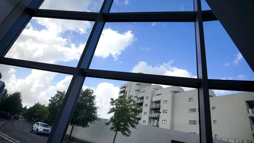 a view of a street through a window, a picture, inspired by Leandro Erlich, unsplash, visual art, low angle facing sky, schools, glass and steel, viewed from the ground