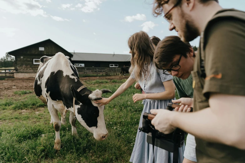 a group of people standing around a cow, pexels contest winner, cottagecore, humans exploring, milk, film footage