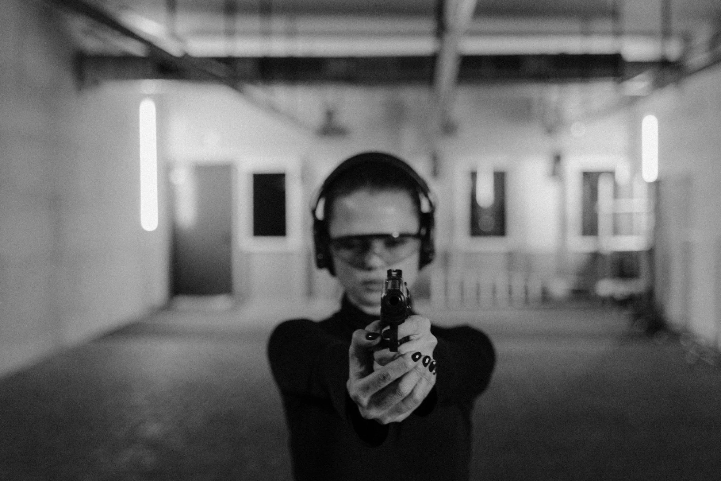 a black and white photo of a woman holding a gun, by Emma Andijewska, unsplash, performance, neo from the matrix, first person weapon, digital art #oneshotgame