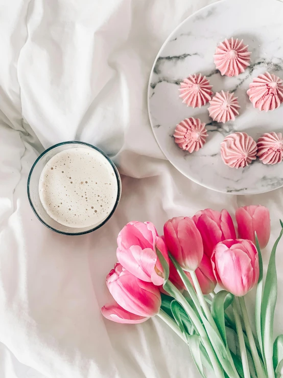 a white plate topped with pink flowers next to a cup of coffee, milkshake, wearing white pajamas, background image, covered with pink marzipan