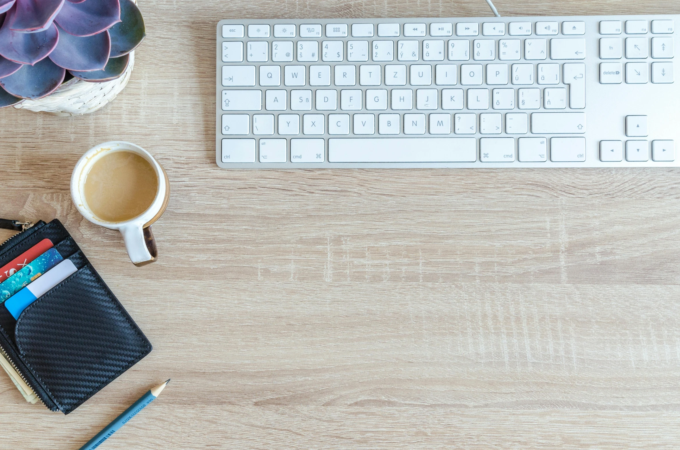 a computer keyboard sitting on top of a wooden desk, by Carey Morris, trending on pexels, white, 9 9 designs, background image, table in front with a cup