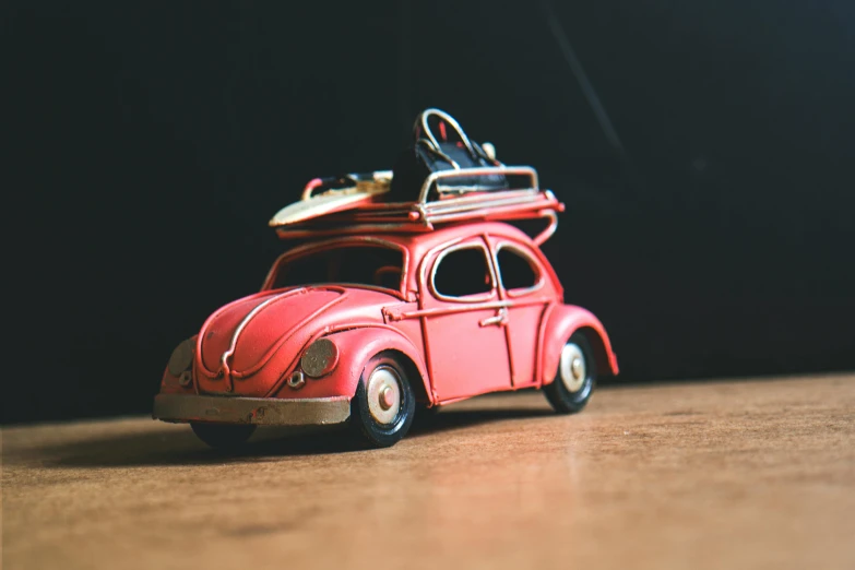 a toy car with a surfboard on top of it, by Adam Marczyński, pexels contest winner, photorealism, pink iconic character, beetle, die - cast metal, vintage old