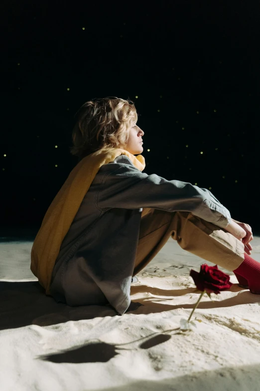 a woman sitting on top of a sandy beach, an album cover, trending on pexels, magical realism, sophia lillis, night under the starry sky, blonde boy with yellow eyes, side profile shot