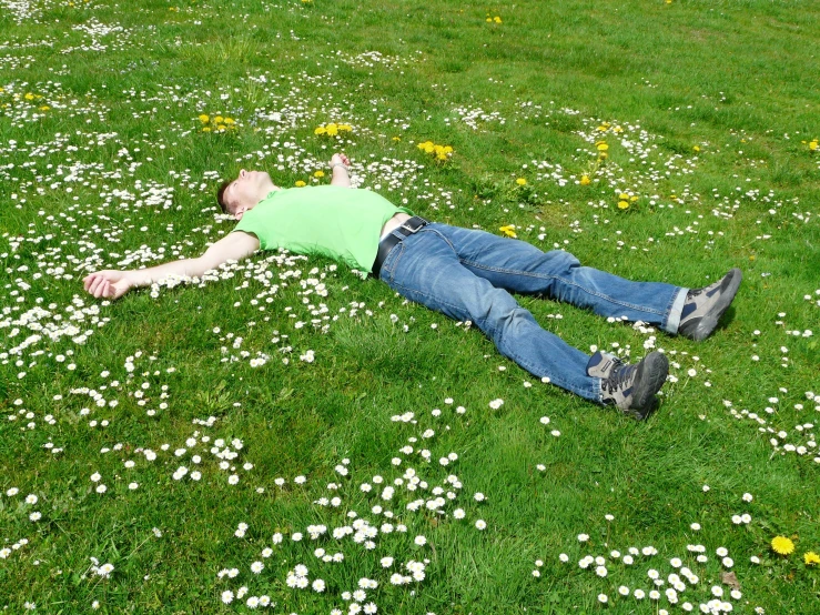 a man laying on top of a lush green field, lying on a bed of daisies, in scotland, float