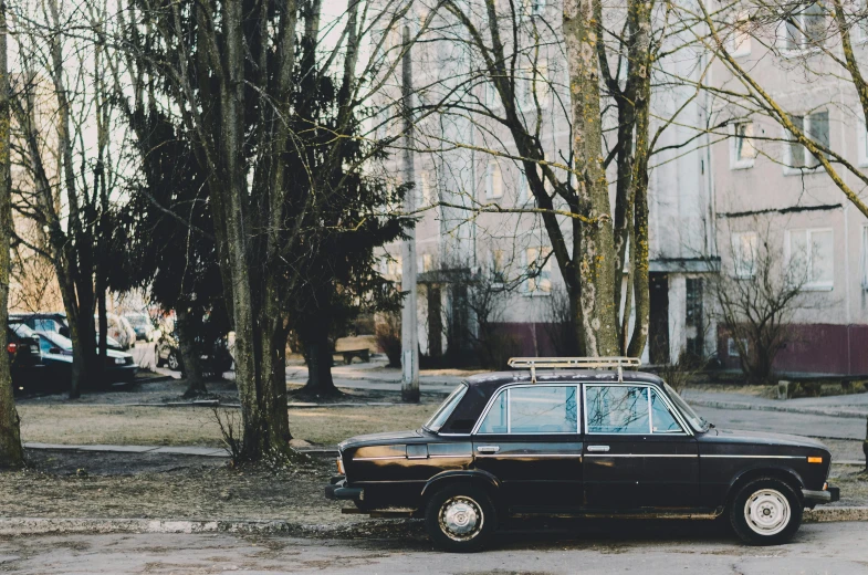 a black car parked on the side of the road, inspired by Elsa Bleda, pexels contest winner, realism, soviet suburbs, 🚿🗝📝, trees in the background, 1 9 8 0 s photo