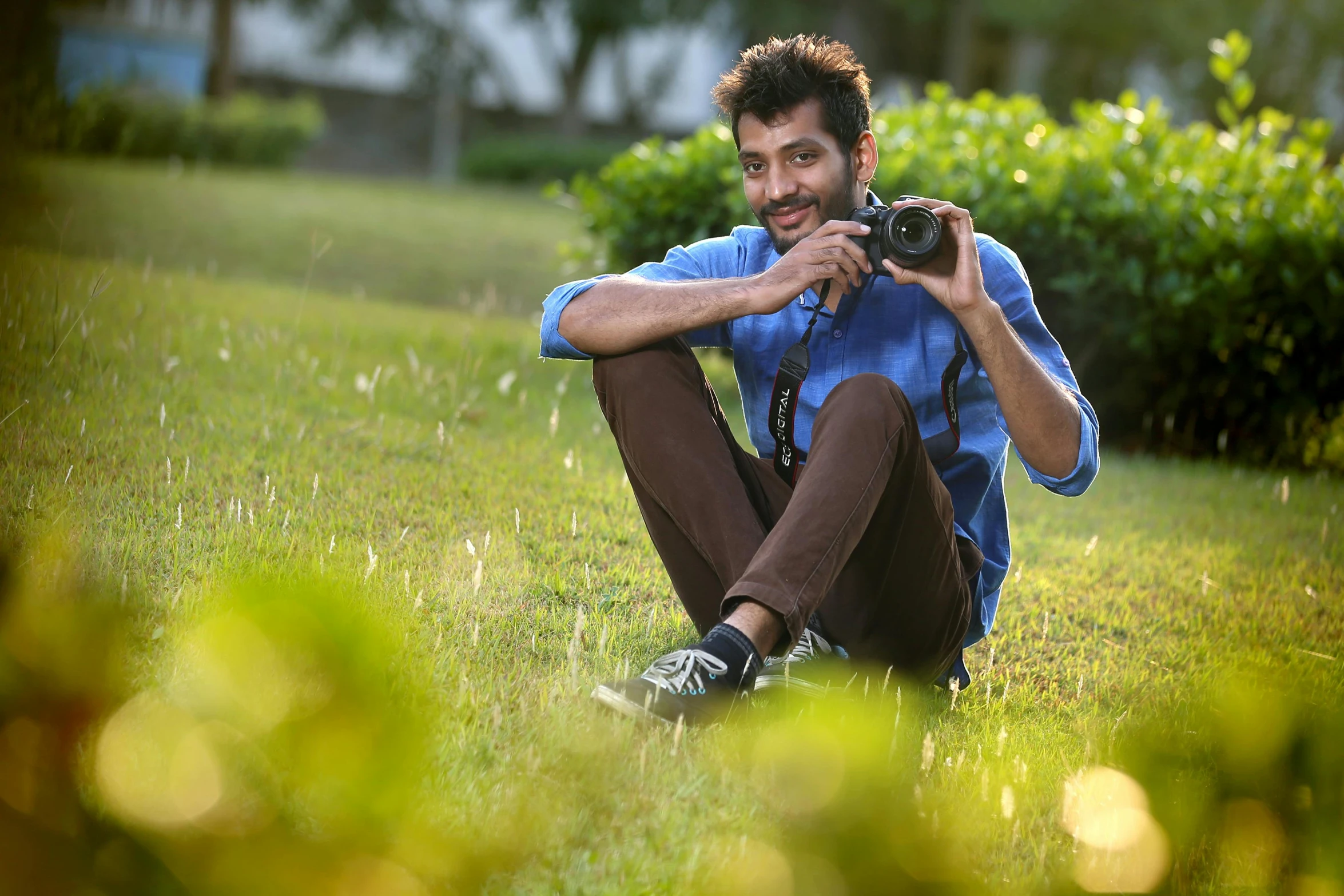 a man sitting in the grass with a camera, by Max Dauthendey, candid picture, avatar image, cute photo, pr shoot