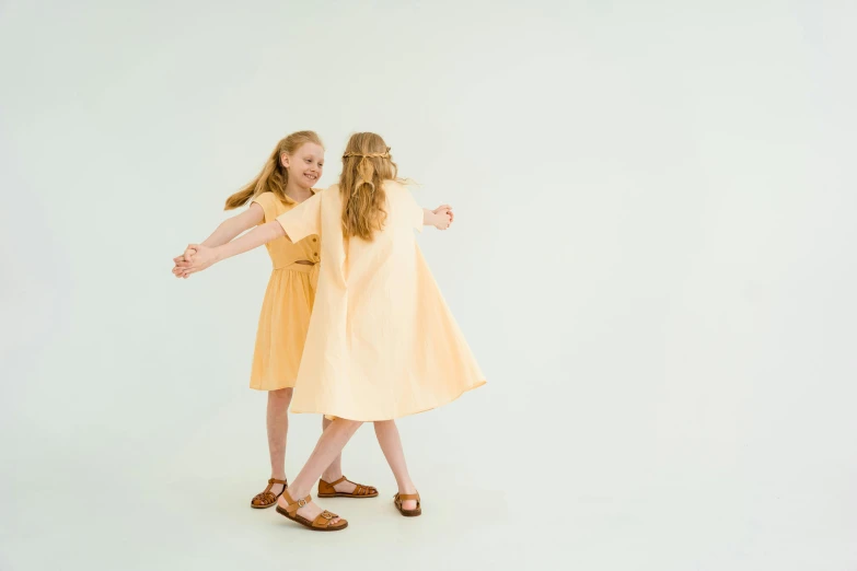 a couple of little girls standing next to each other, by Ruth Simpson, unsplash, conceptual art, light yellow, as though she is dancing, on the white background, young teen