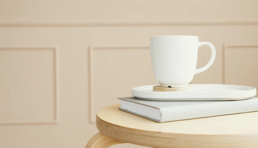 a white coffee cup sitting on top of a stack of books, inspired by Agnes Martin, trending on pexels, minimalism, cafe tables, detail render, on a wooden tray, detailed product image