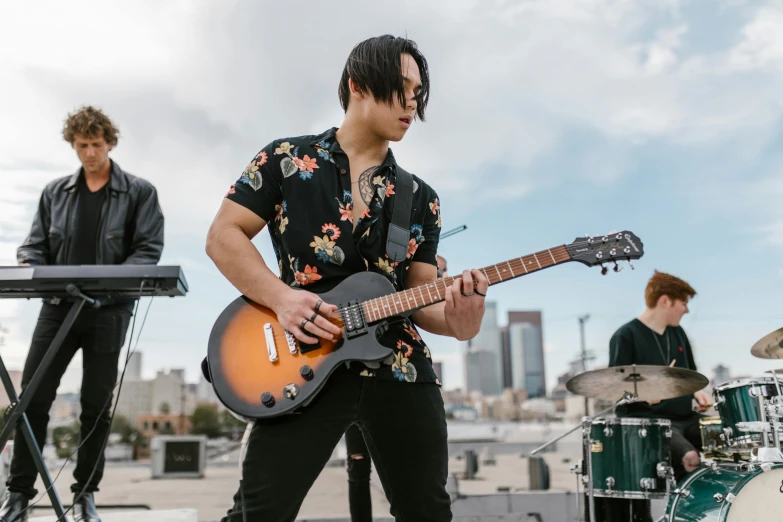 a group of young men playing instruments on a stage, pexels contest winner, realism, standing on a skyscraper rooftop, taejune kim, playing a gibson les paul guitar, half asian