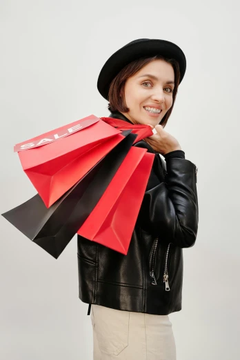 a woman in a leather jacket holding shopping bags, pexels contest winner, red hat, promo image, david bailey, neoprene