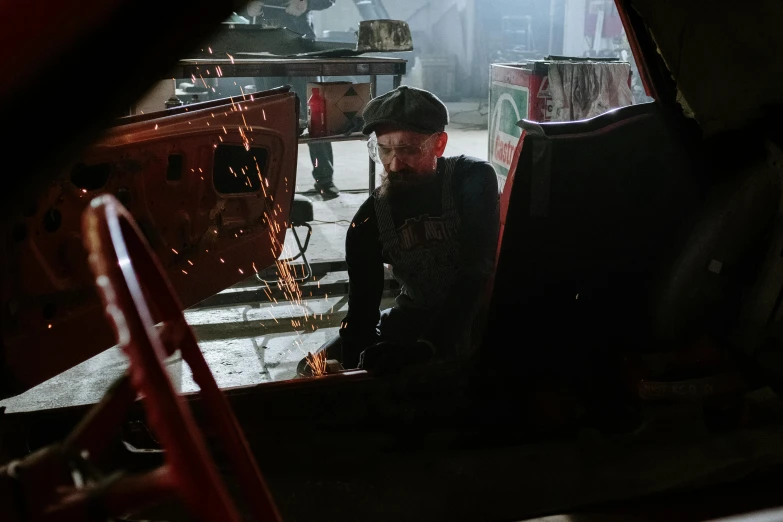 a man working on a car in a garage, a portrait, pexels contest winner, auto-destructive art, costumes from peaky blinders, harley quinn film still, welding torches for arms, bearded and built