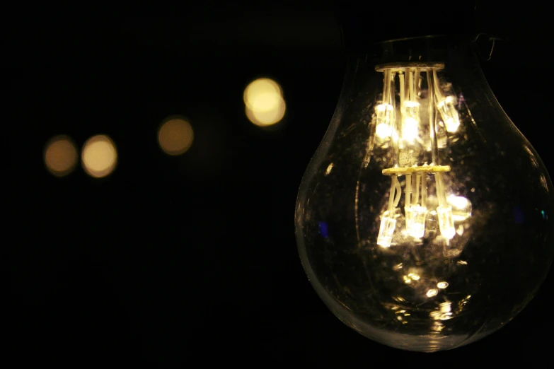 a light bulb is lit up in the dark, pexels, bokeh. i, ilustration, laura watson, electrical