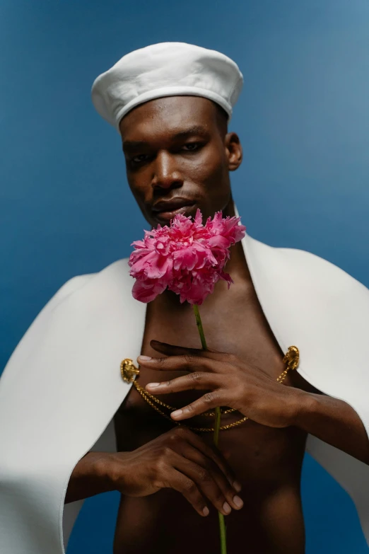 a man in a white robe holding a pink flower, an album cover, inspired by Barthélemy Menn, unsplash, afrofuturism, patrick demarchelier, very very roberto ferri, with a gold crown, catalog photo