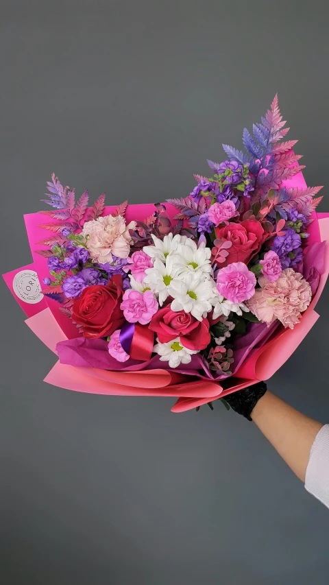 a close up of a person holding a bunch of flowers, purple and pink, perfect design, on a gray background, (pink colors)