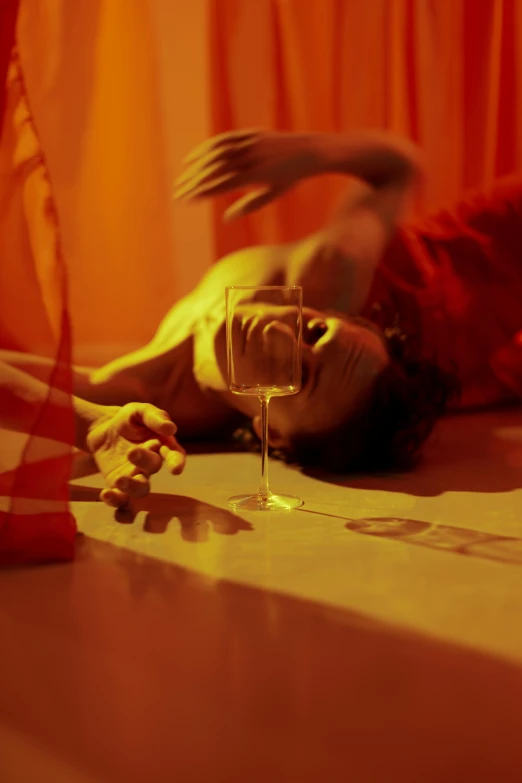 a person laying on the floor with a glass of wine, inspired by Nan Goldin, serial art, suspiria, shades of aerochrome gold, cut-scene, ignant