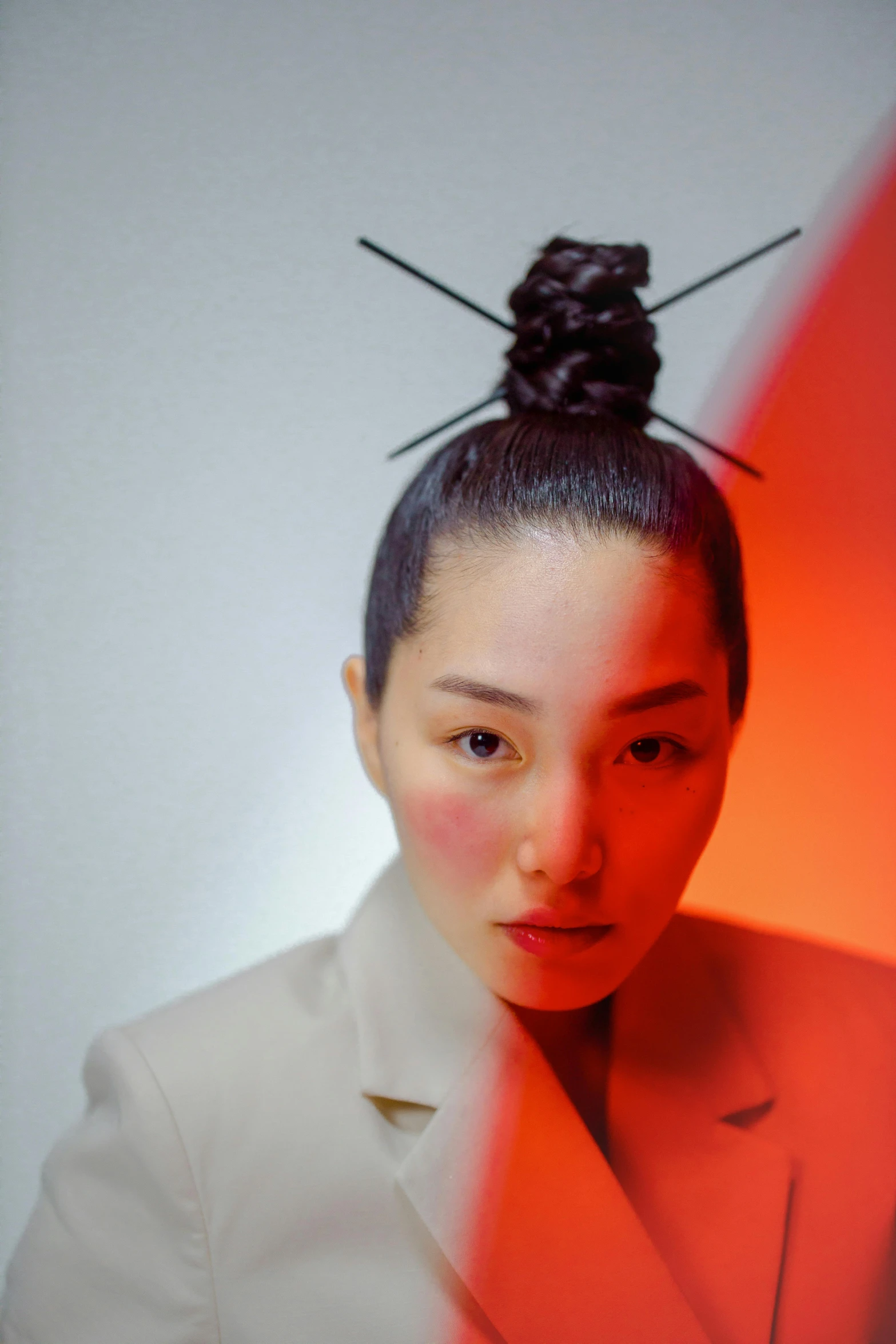 a woman in a white jacket posing for a picture, an album cover, inspired by Gao Cen, unsplash, with dark hair tied up in a bun, red hue, looking into camera, nanae kawahara