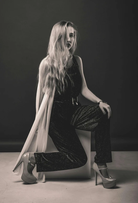 a black and white photo of a woman sitting on a chair, a black and white photo, unsplash, art nouveau, billie eilish, long golden hair, studio medium format photograph, standing elegantly